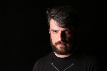 Bearded man in T-shirt with serious look. Close.up. Black