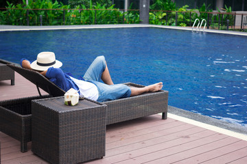 man lying on deck chairs next to a swimming pool
