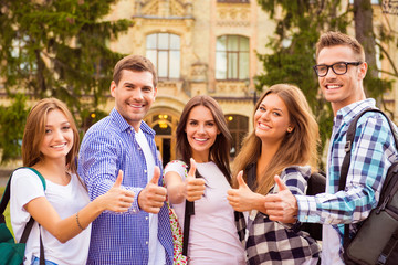 diverse five joyful friends showing thumbs up standing near camp