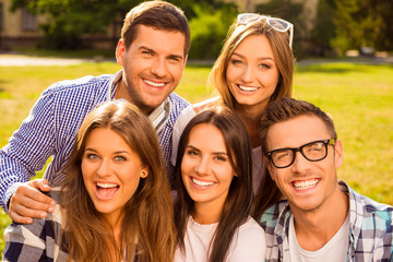 cheerful five friends hug and rest at sunny day