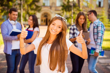 excited happy girl standing near university and her friends and