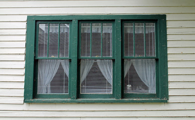 Fototapeta na wymiar Three Green Windows in an Old White House