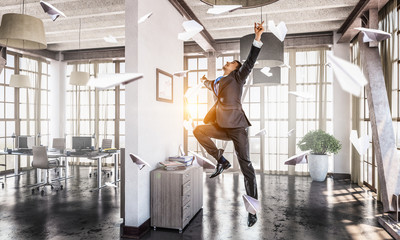 Jumping businessman in office . Mixed media