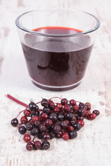 Bunch of fresh elderberry with juice on old wooden background, healthy nutrition