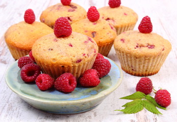 Fresh baked muffins with raspberries on old wooden background, delicious dessert