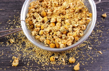 Dried chamomile on metal sieve, alternative medicine