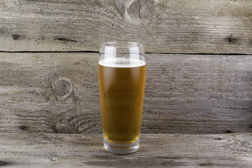 Glass of light beer on wooden background