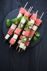 Above view of fruit skewers on a black wooden background