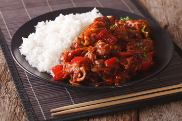 Pork braised in sweet and sour sauce with vegetables and rice close-up. horizontal
