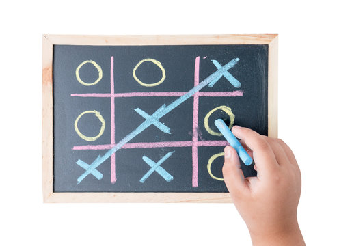 boy hand drawing a game of tic tac toe on a black chalkboard