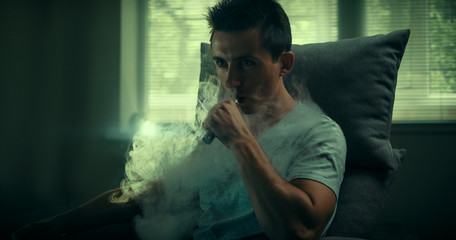 Stylish vaper. Young guy. Man using an advanced personal vaporizer or e-cigarette. 