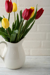 Red and yellow tulip in white jug