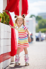Cute little red-haired girl with hair in two ponytails,grey eyes,dressed in a multicolored striped...