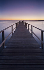 Fototapeta na wymiar Wooden Pier into a Lake at Sunset, perfect symmetry