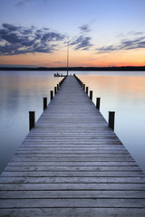 Meer bij zonsondergang, lange houten pier