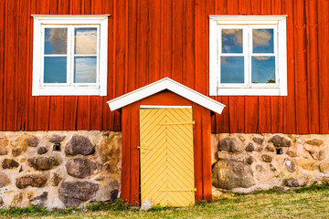 Lovely vintage yellow door on a bright red house with white details. - 118163862
