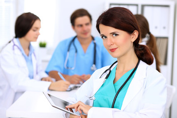 Happy doctor woman  with medical staff at the hospital sitting at the table and discussing medical history