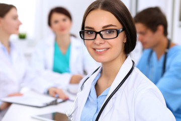 Happy doctor woman  with medical staff at the hospital sitting at the table and discussing medical...