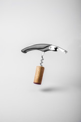 Wine cork and bottle opener floating on white background