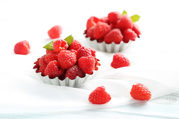 Red raspberries in bowl on a white wooden table