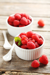Red raspberries in bowl on a grey wooden table