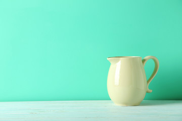 Beige jug on a green wooden table
