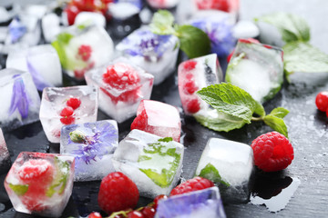 Ice cubes with raspberries and mint leaf on wooden table