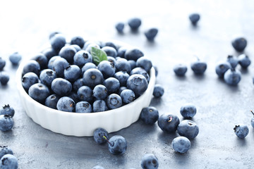 Ripe and tasty blueberries on grey wooden table