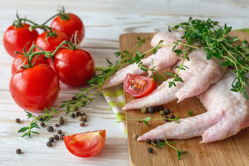 Raw chicken wings with thyme, chili, pepper and tomatoes
