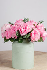 florist did rich bunch flowers light background, wooden surface. green vase