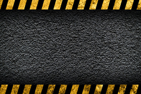 Grunge dark grey background with black and yellow warning stripes