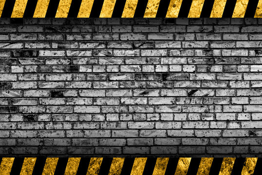 Grunge grey brick wall background with black and yellow warning stripes