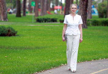 женщина в возрасте с гаджетом в руках гуляет по парку