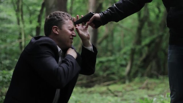 Businessman kneels in the woods and begs for mercy thug. Montage.