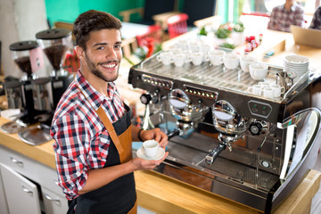 Satisfied male waiter holding cup