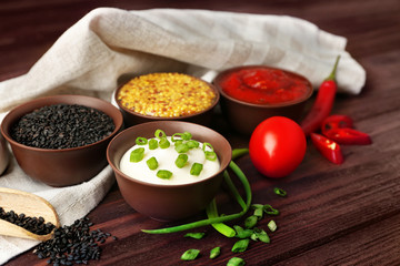 Fresh condiments and sauces on wooden background