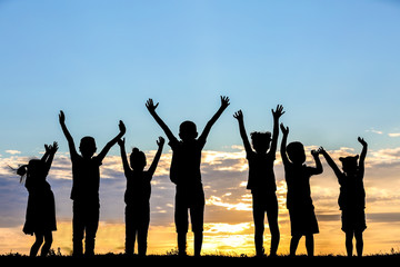 Happy kids silhouettes on sunset background