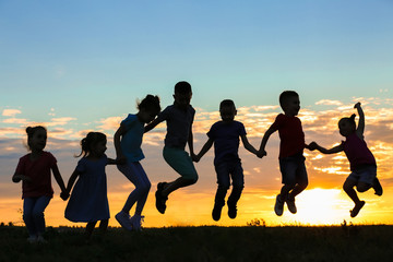 Happy kids silhouettes on sunset background