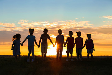 Happy kids silhouettes on sunset background