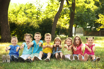 Fototapeta na wymiar Happy kids sitting on grass in park