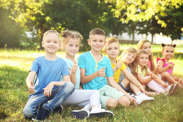 Fototapeta premium Happy kids sitting on grass in park