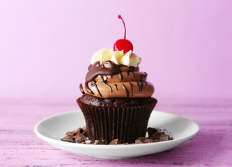 Tasty chocolate cupcake with berries on purple background
