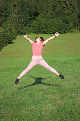 happy little girl jumping on field