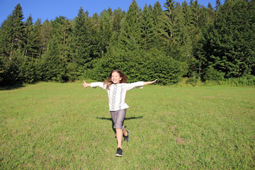 happy little girl running on green grass field