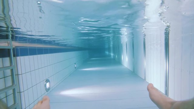 Male legs in swimming pool. Underwater footage clip of feet in refreshment pool.