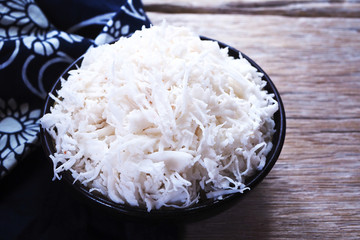 Shredded coconut in a bowl on a wooden table.