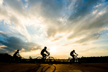 Obraz premium Silhouette of cyclist with friend motion on sunset background
