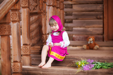 Fototapeta na wymiar Petite Russian beauty sits on a wooden porch