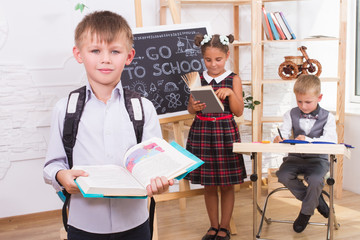 Portrait of a boy reading a book on the background of their classmates
