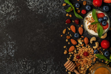 Fototapeta na wymiar Tasty ingredients (granola, honey, berries, yogurt and nuts) for